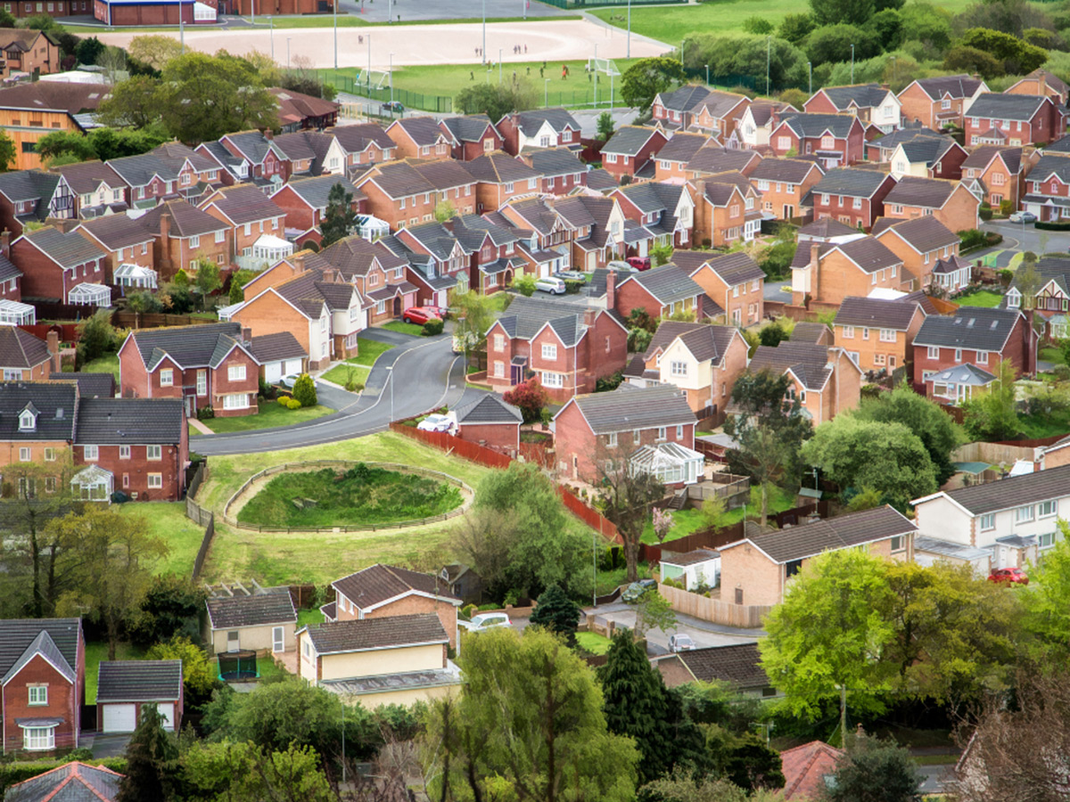 Aerial shot of a new build housing estate surrounded by green trees